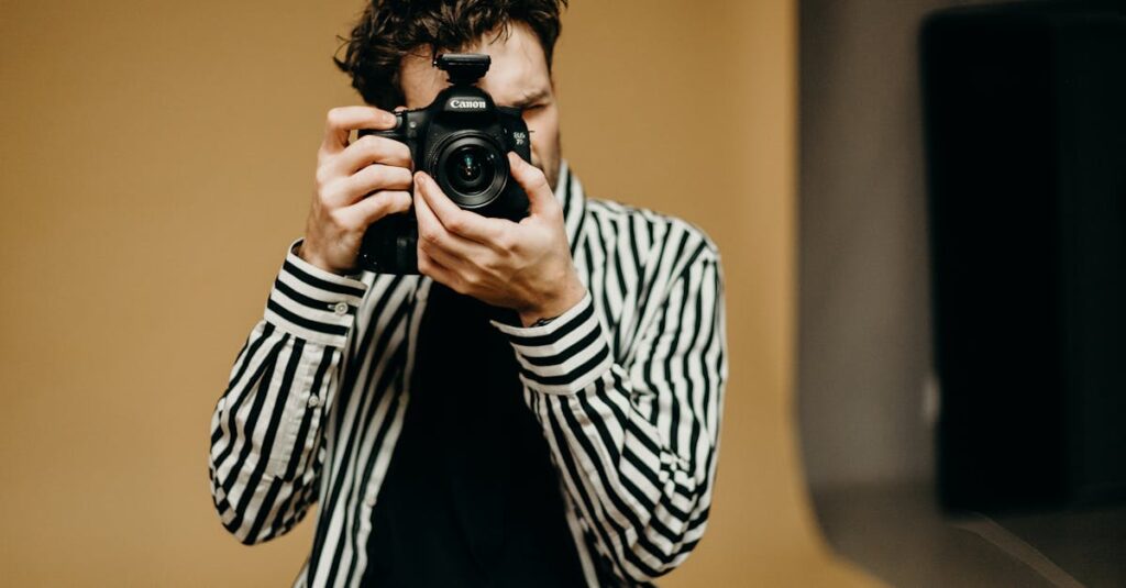 Portrait of a young male photographer using a DSLR camera in an indoor studio setting.
